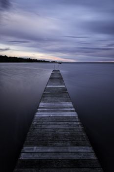 Pier into the Ocean at sunset with clouds.