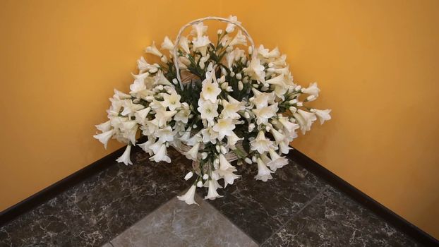 a basket of beautiful white flowers standing in the corner.
