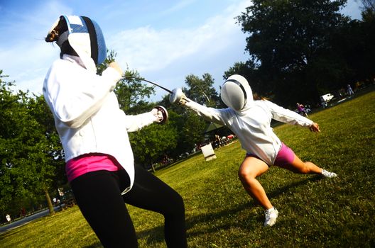 Two girls performing fencing in the park