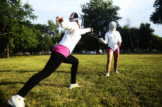 Two girls performing fencing in the park
