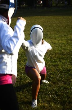 Two girls performing fencing in the park