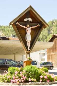 Crucifix over a flowerbed along a road in a valley of the Tyrol in Austria