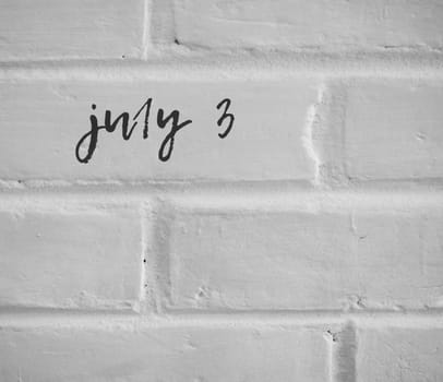 PHOTO OF july 3 WRITTEN ON WHITE PLAIN BRICK WALL
