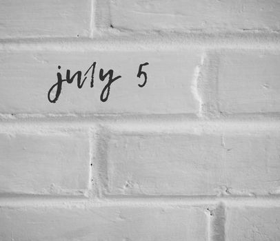 PHOTO OF july 5 WRITTEN ON WHITE PLAIN BRICK WALL
