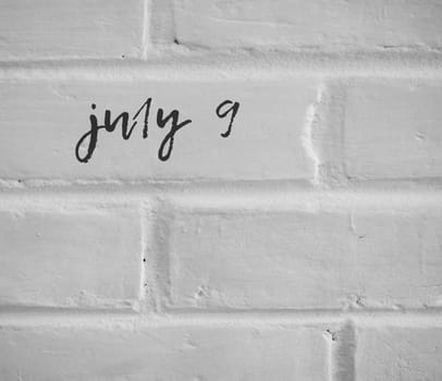 PHOTO OF july 9 WRITTEN ON WHITE PLAIN BRICK WALL