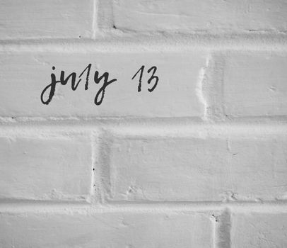 PHOTO OF july 13 WRITTEN ON WHITE PLAIN BRICK WALL