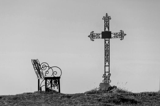 Graveyard cross in silhouette against a blue sky