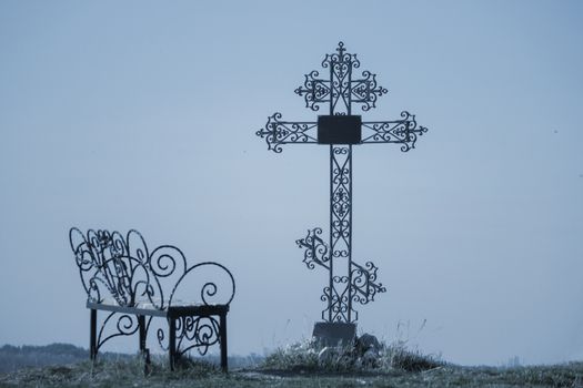 grave and a bench under ortodox cross