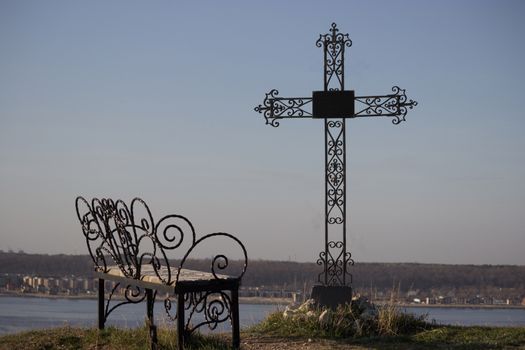 Graveyard cross in silhouette against a blue sky