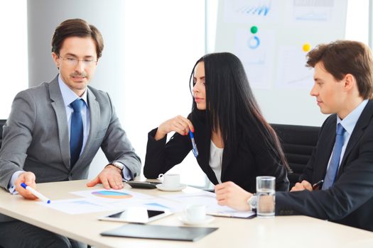 Workers at business meeting looking at presentation of financial reports in modern office