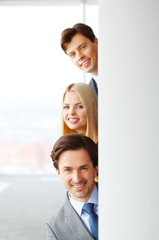 Happy business people looking out from corner in office