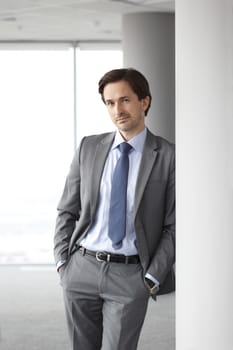 Portrait of handsome businessman standing near windows in office