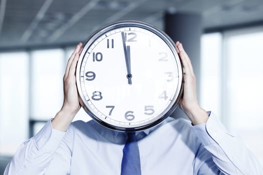 Man holding wall clock in office, deadline concept