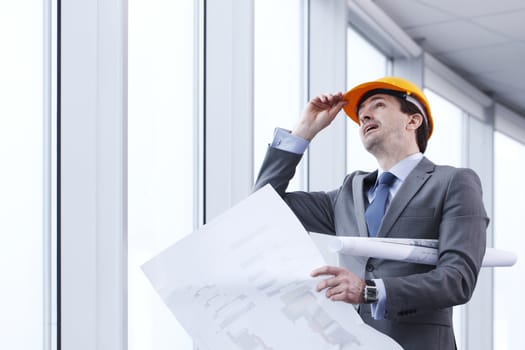 Architector in hardhat and business suit with construction plans