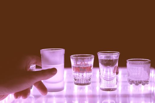 many shot on illuminated table. hand grab one shot