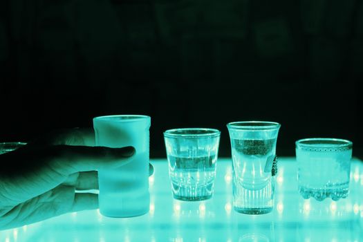 many shot on illuminated table. hand grab one shot