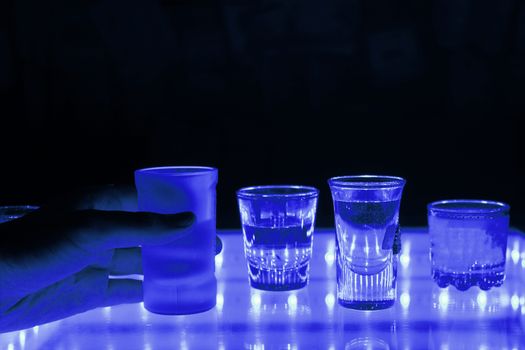 many shot on illuminated table. hand grab one shot