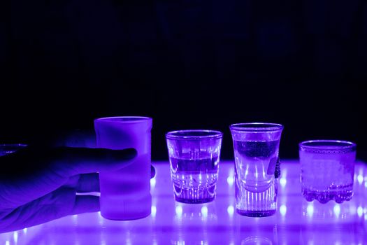 many shot on illuminated table. hand grab one shot