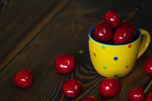 Fresh cherries in jar on the wooden background. Selective focus. Focus on the right cherries in front of jar.