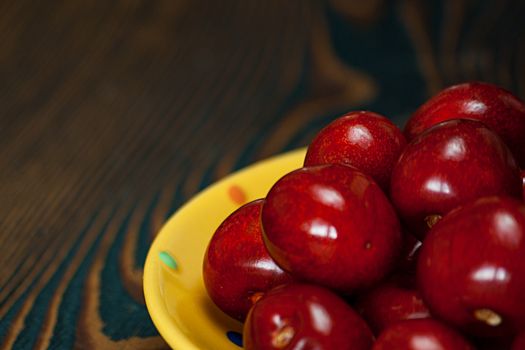 Fresh cherries in jar on the wooden background. Selective focus. Focus on the right cherries in front of jar.