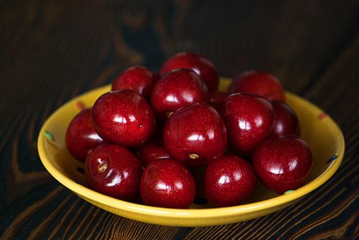 Fresh cherries in jar on the wooden background. Selective focus. Focus on the right cherries in front of jar.