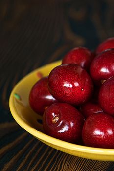 Fresh cherries in jar on the wooden background. Selective focus. Focus on the right cherries in front of jar.