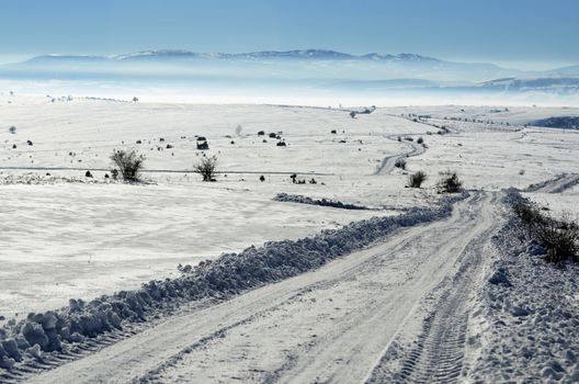 Landscape of road on the empty field covered with snow and ice on sunny day
