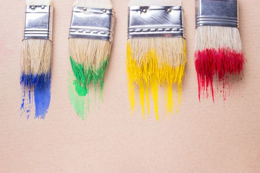 Different sizes paintbrushes against a background of multicolored paint spread.