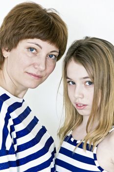 Mother and daughter playing with blond long hair near white wall