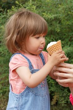 Cute baby girl are eating icecream in summer with put out tongue