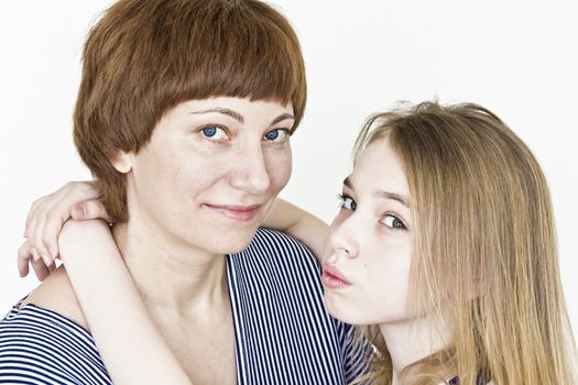 Mother and daughter playing with blond long hair near white wall