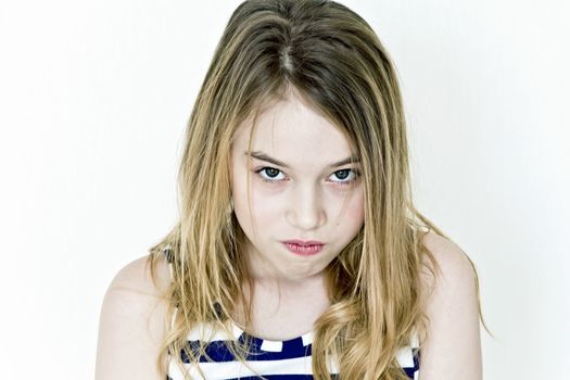 Cute angry girl with blond long hair on white wall in striped clothes