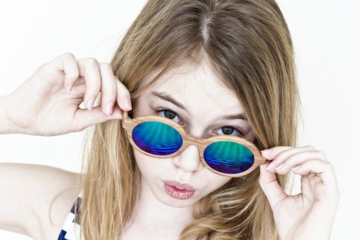 Girl eleven years old standing near white wall with green sunglasses