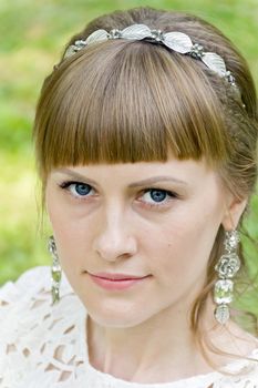 Portrait of blue eyes and blond hair bride with diadem on green background