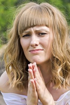 Young praying woman with blond hair in sunlight