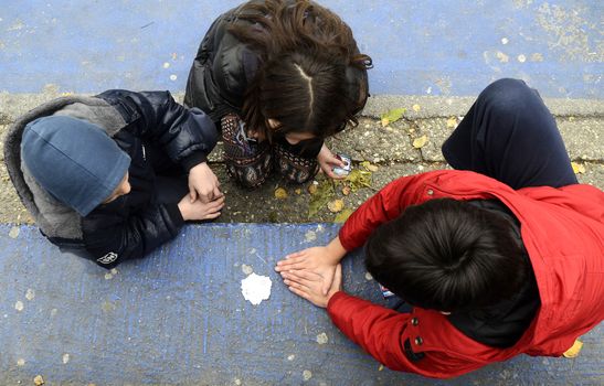 Three kid playing with hands outside on cold day