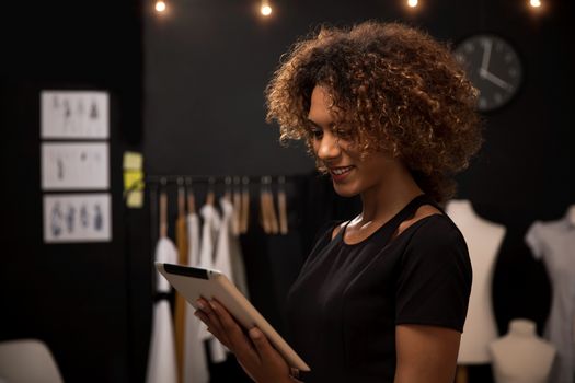 A young fashion designer on her atelier working with a tablet