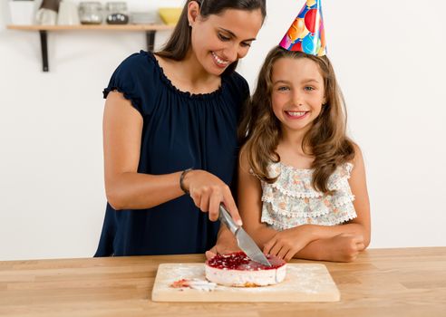 Shot of a mother and daughter cuting the cutting the birthday cake