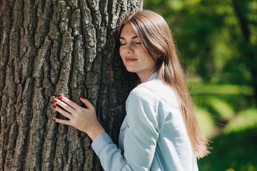 Young woman hugging a big tree, love nature concept