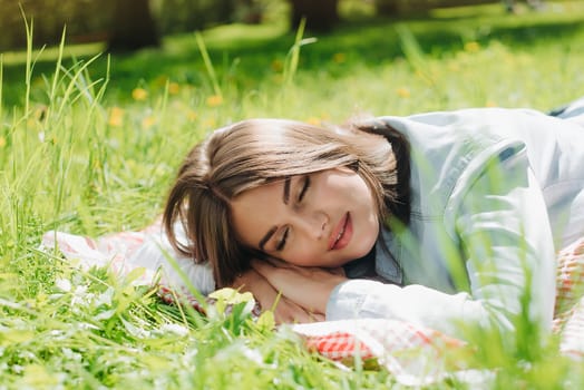 Beautiful young woman sleeping on fresh spring grass in park