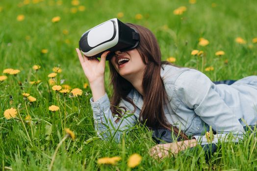 Woman using the virtual reality headset outdoors laying in spring flower field