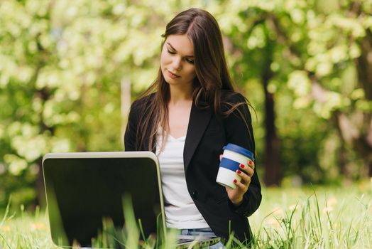 Beautiful business woman in suit using laptop computer in the park