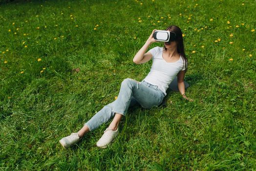 Woman using the virtual reality headset outdoors laying in spring flower field