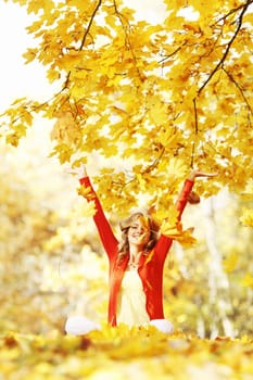 Happy woman in autumn park drop up leaves