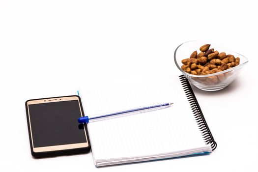 mobile phone and notebook on the desk with bowl of huzelnuts for keeping energy while working
