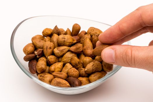 person taking pealed hazelnuts out of the glass bowl