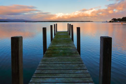 Old timber jetty with green mossy planks in the sunset