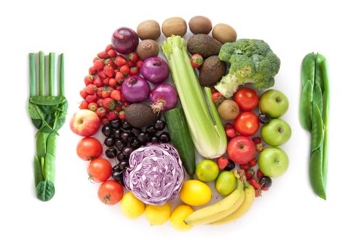 Fork and knife and miniature fruits and vegetables packed together in the shape of a plate