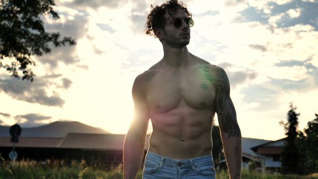 Handsome Muscular Shirtless Hunk Man Outdoor in Country Standing on Grass. Showing Healthy Muscle Body While Looking away