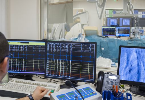 Monitors with heartbeat rate and x-ray image in modern hospital operating room.